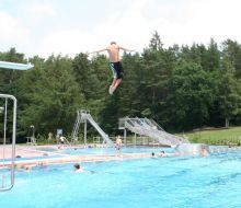 Ein Junge springt vom 3m-Brett ins Wasser