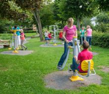 Personen betaetigen sich an Outdoor-Fitnessgeräten