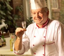 Ein Koch hält ein Glas Sekt in die Kamera 