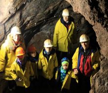 Eine Familie mit Helmen und Regenmaenteln vor Steinwaenden in der Grube Christiane