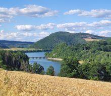 Blick über Getreidefeld zum Diemelsee mit Brücke nach Stormbruch
