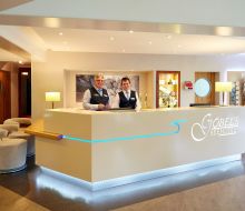 Hinter dem Rezeptionstresen stehen zwei freundliche Männer 