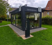 Ein verglastes Geb&auml;ude mit historischer Ausstellung zum Thema Waschen, davor eine Reparaturs&auml;ule