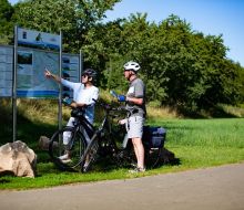 Radlerpärchen steht vor einer Infotafel 