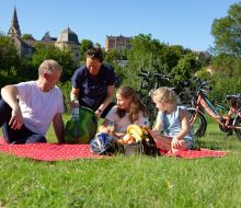Familie sitzt auf einer Decke auf einer Wiese, im Hintergrund Altstadt Warburg