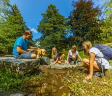 Eine Familie sitzt an der Diemelquelle bei Usseln