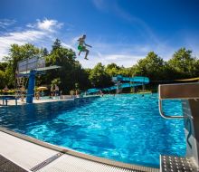 Ein Junge springt vom 3m Brett ins blaue Becken